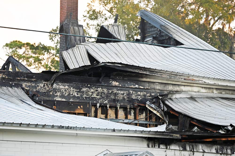Asphalt shingles beneath the metal roof had kept burning much of the night. (© FlaglerLive)