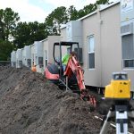 A crew this morning worked on installing water and sewer connections to seven used portables just delivered to Buddy Taylor Middle School, re-starting a trend the district had hoped to avoid. (© FlaglerLive)