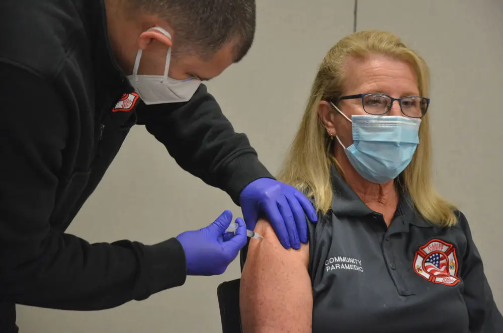 Caryn Prather, Flagler County Fire Rescue's Community Paramedic and one of the leaders of the county's 10-months-long Covid-testing program, getting her first dose of the Moderna vaccine on Tuesday at the Emergency Operations Center. She was one of about 20 people inoculated. (© FlaglerLive)