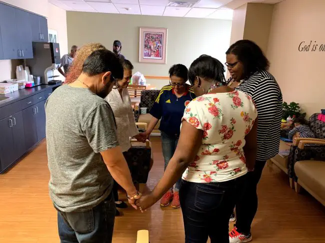 A moment of prayer in the ICU waiting room, with Anthony's mother, Erika Williams, and her mother, toward the center, and Anthony's uncle Carlos Trivino to the left. (© FlaglerLive)