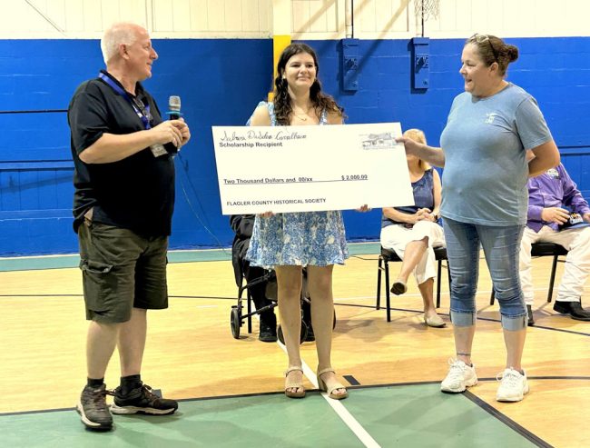 Ed Siarkowicz, president of the Flagler County Historical Society, and Tonya Gordon, vice president of the society, presented a $2,000 check to Palm Coast resident and University of North Florida student Sabrina DaSilva-Carvalheira as the winner of the society’s scholarship competition. FlaglerLive photo