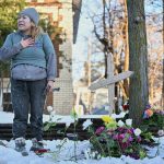 A protester stands near a makeshift memorial honoring Renee Nicole Good, the victim of a fatal shooting in Minneapolis involving federal law enforcement agents.