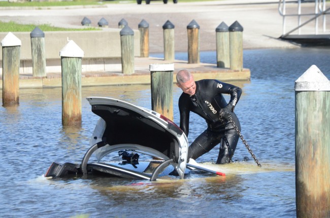 Cpl. Jon Reckenwald, a certified diver and the supervisor of the Flagler County Sheriff's Marine/Dive Unit, prepares the Kia for the wreckers to pull from the water this morning at Hershel King Park. Click on the image for larger view. (c FlaglerLive)