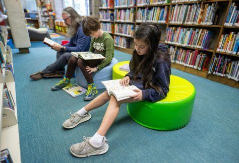 Children and an adult read books at the Altadena Main Library in Altadena, Calif., in March 2025.