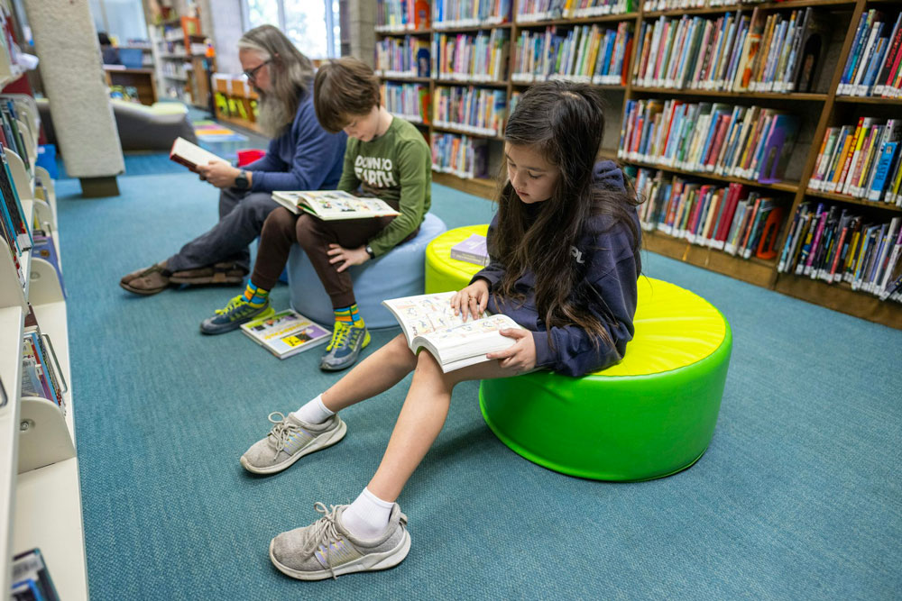 Children and an adult read books at the Altadena Main Library in Altadena, Calif., in March 2025.
