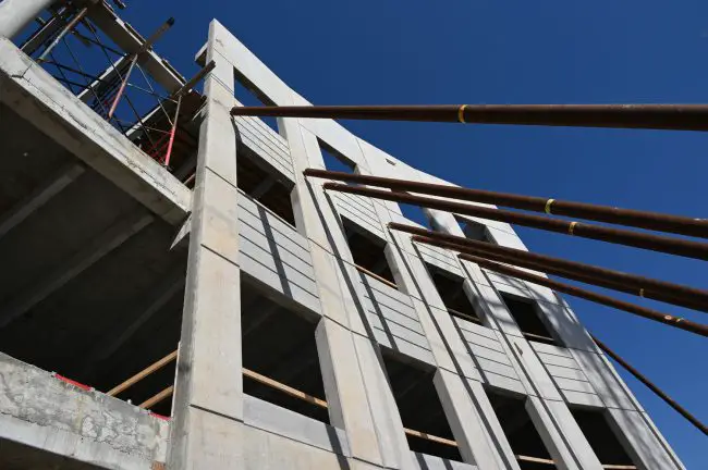 Tilt-up concrete panels, built on site of concrete, rebar and insulation, are 9 inches at the bottom, 12 inches just above the first level. They are being held up by braces until an additional floor is in place. (© FlaglerLive)