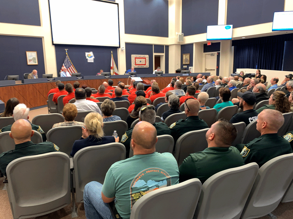 The red and the green--firefighters and cops--filled the county commission's chamber at a meeting this afternoon. (© FlaglerLive)