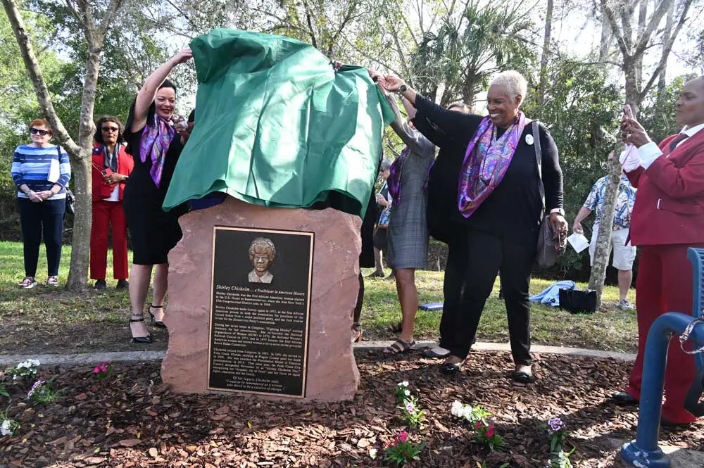 Jill Reynolds, left, and Marva Jones unveiling the bronzel plaque commemorating the Shirley Chisohlm Trail along Pine Lakes Parkway this morning. (© FlaglerLive)