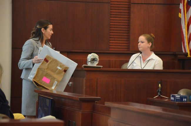 Assistant State Attorney Jennifer Dunton, left, showed Flagler Sheriff's CSI investigator Lainie Rittenour evidence that included a section of piping that had been found drawing exhaust fumes into the car in which Kathryn Goddard was found dead, and Bruce Haughton unconscious. Click on the image for larger view. (© FlaglerLive)