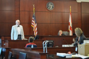 Pathologist and former medical examiner Ronald Wright, standing, was asked by Assistant State Attorney Jacquelyn Roys whether the angle of a shiot from a tall man (like Miller) would not have a downward trajectory, a contention Wright only relectantly and conditionally conceded. Circuit Judge J. David Walsh is presiding. Click on the image for larger view. (© FlaglerLive)