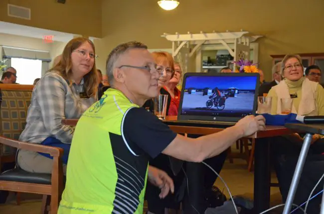 Ildus Yanyshev showing various video clips from his trip at Tuesday's Rotary Club lunch, with Supervisor of Elections Kaiti Lenhart to his left, and club member Thea Mathen to his right. (© FlaglerLive)