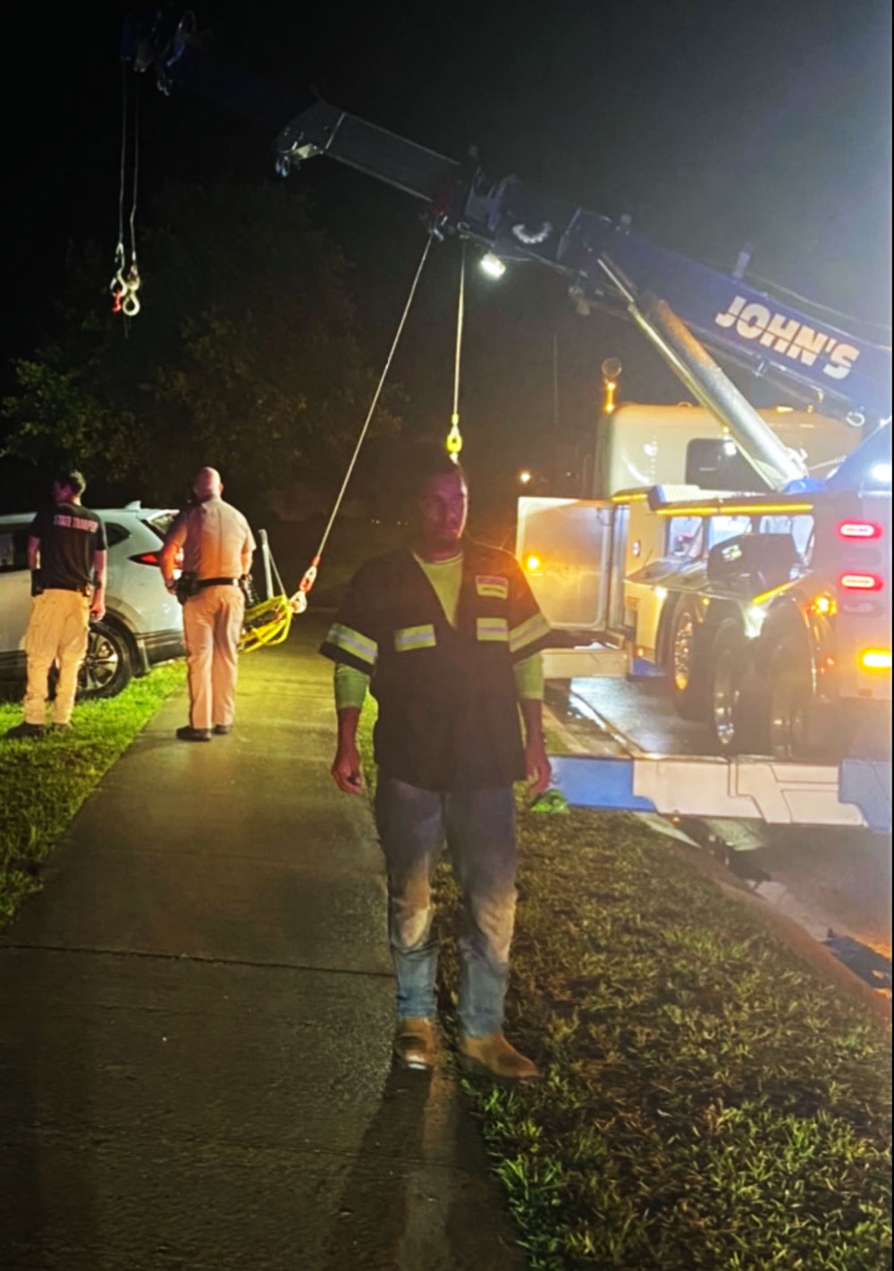 Trey Russell, one of the John's Towing employees at the scene, with the 50-ton Rotator Wrecker in the background used to pulled the vehicle out of the pond. (© John's Towing)
