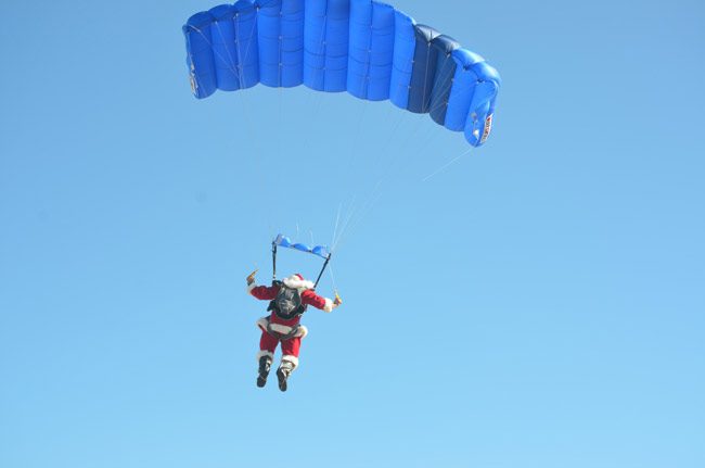 Santa parachutes down to launch the parade at 1 p.m. near the pier. (© FlaglerLive)