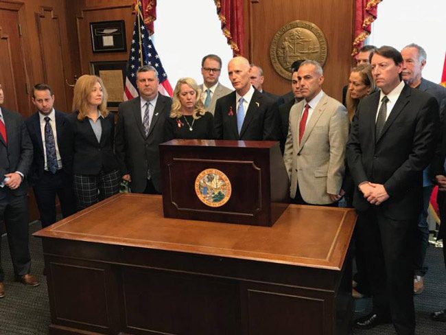 Gov. Rick Scott was flanked by parents of teenagers killed at Marjorie Stoneman Douglas High School on Valentine's Day when he signed the school-safety law. (NSF)
