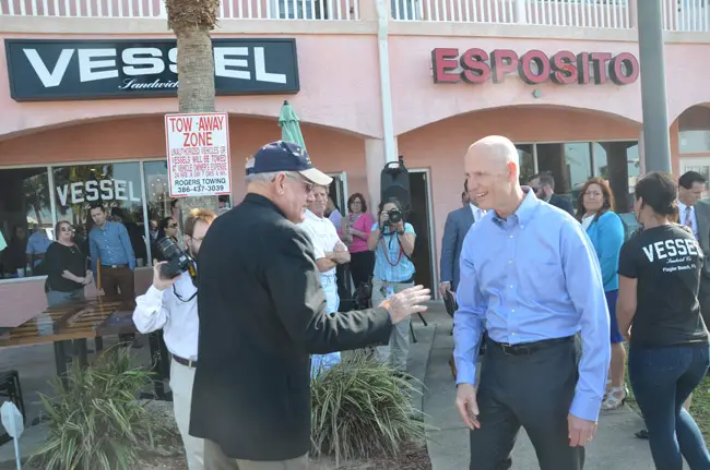 Gov. Rick Scott, right, during his last visit to Flagler County, when he was campaigning in favor of a $100 million budget for Visit Florida. He is seen here speaking with County Commissioner Dave Sullivan in Flagler Beach. (© FlaglerLive)