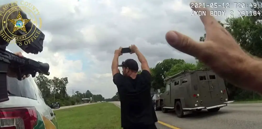 With numerous weapons trained on him, Joshua Siedel was intent on protecting his phone down to the last moment before he was handcuffed after a two-hour standoff on U.S. 1 Wednesday afternoon. (© FlaglerLive via FCSO video)