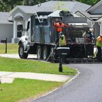 A crew applying an asphalt sealant on a P-Section street in April. The sealant is a lower-grade, cheaper alternative to repaving. It is intended to extend the life of a street's surface by several years. (© FlaglerLive)