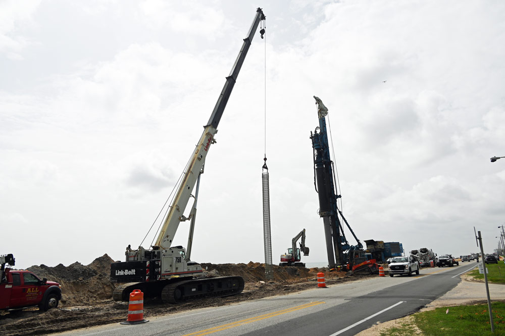 The drill at right that creates the 18- and 36-ft. holes, filling them with concrete, before reinforced rebar (the cylindrical object in the center) is pushed through the concrete, forming a segment of the secant wall. Workers were on the job in Volusia County's portion of the wall today. Flagler County's wall is nearly complete. (© FlaglerLive)