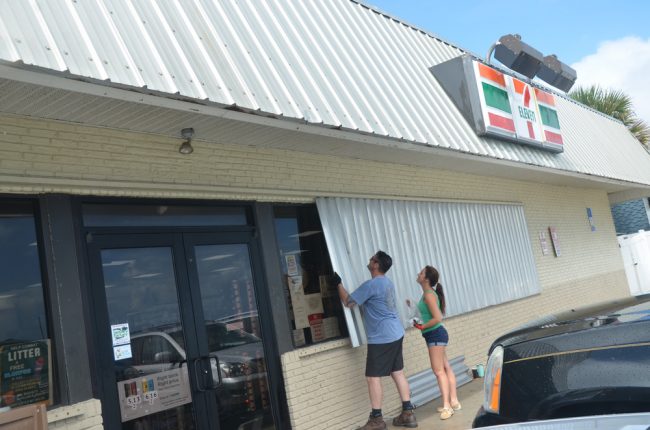 Flagler Beach City Commissioner Eric Cooley, owner of the 7-Eleven on South Oceanshore Boulevard in Flagler Beach, boarding up the business with Suzy Johnston this afternoon. He excpects the store to be the last to close and the first to open on either side of the Dorian emergency, with generators keeping coffee hot and sodas cold. (© FlaglerLive)