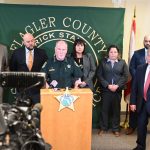 Flagler County Sheriff Rick Staly, at the podium, speaking with the detectives of the Major Crimes Unit who resolved the case--from left, detectives Augustin Rodriguez, George Hristakopoulos, Chief Kim Burroughs, who heads the investigative division, detectives Jordan St. John and Daniel Laverne. (© FlaglerLive)