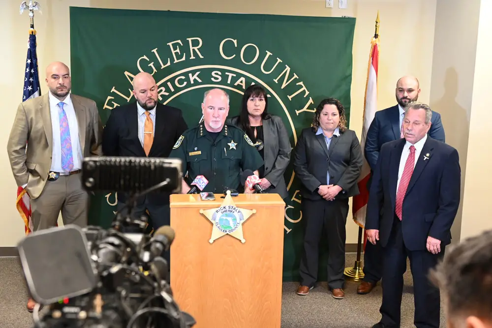 Flagler County Sheriff Rick Staly, at the podium, speaking with the detectives of the Major Crimes Unit who resolved the case--from left, detectives Augustin Rodriguez, George Hristakopoulos, Chief Kim Burroughs, who heads the investigative division, detectives Jordan St. John and Daniel Laverne. (© FlaglerLive)