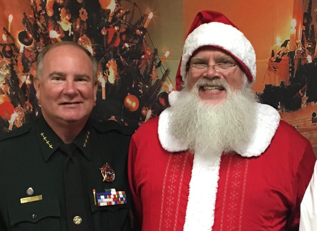 Sheriff Rick Staly ran into Santa at WNZF's Christmas party Monday evening, and thanked Santa for granting his wife's wish--that Staly win the sheriff's race so he'd have reasons to leave the house. Santa in this case was Palm Coast Little League's president, Patrick Johnan. (David Ayres)