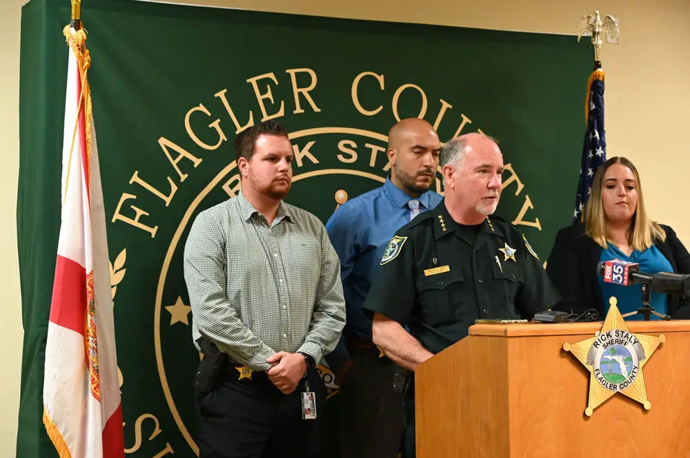 Sheriff Rick Staly announcing the charge against Robert Hill today with the detectives who worked the case. From left, Gabe Fuentes, Augustin Rodriguez, and the lead detective, Sarah (© FlaglerLive)