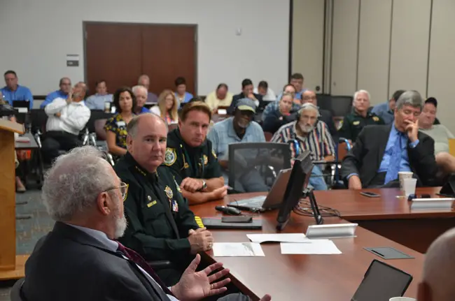 Sheriff Rick Staly, toward the left, listened to Council member Bob Cuff after the sheriff's presentation to the council this morning, with Palm Coast Precinct Commander Mark Carman at his side and, toward the right, City Manager Jim Landon. (© FlaglerLive)