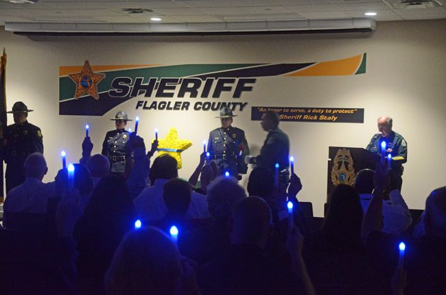 The blue lights in commemoration of fallen officers, raised last night during the Flagler County Sheriff's ceremony in their memory as Sheriff Rick Staly, right, read the names of the fallen in Flagler through history. (© FlaglerLive)