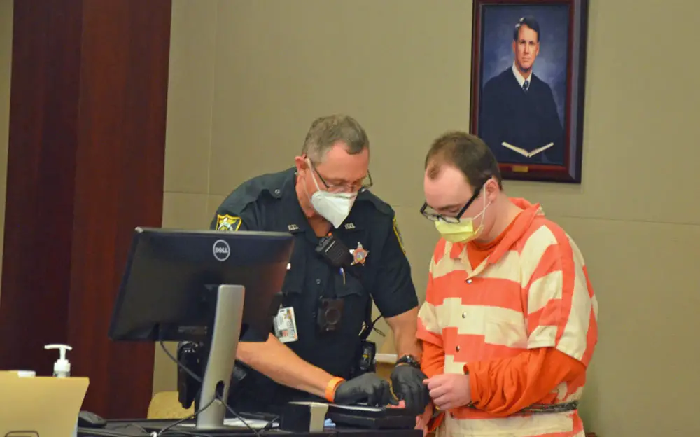 Nathaniel Rider Shimmel getting finger-printed this morning after being sentenced to 50 years in prison in the stabbing death of his mother, Michele, three years ago. (© FlaglerLive)