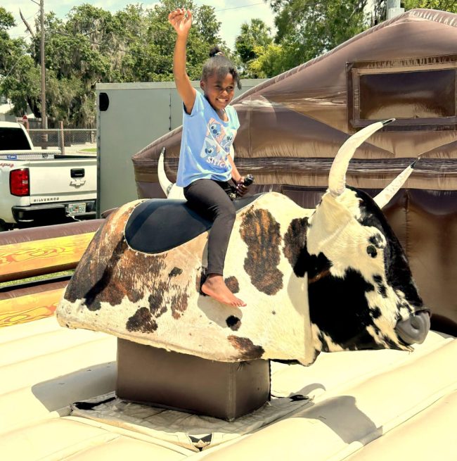 Skylar Gunter, granddaughter of Sonji Jackson, rides the mechanical bull at Bunnell History Day. FlaglerLive photo