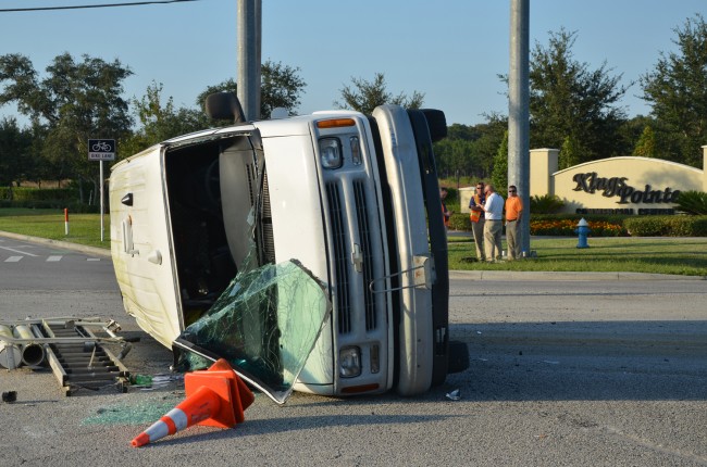 The AT&T van was heading north on Old Kings Road when it was t-boned by a Ford Focus going east on SR100 a little after 5 p.m. today. The driver of the van, in the white shirt near the Kings Pointe sign, kicked out the windshield and escaped injury. (click on the image for larger view. c FlaglerLive)