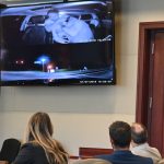 Travis Smith, flanked by his two attorneys, watches himself in footage of his attack on Nihat Aksezer at the aborted end of a Lyft ride Aksezer was giving Smith, his friend and his friend's son in Palm Coast two years ago. Smith is on trial over that attack. (© FlaglerLive)