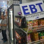 A man shops at El Recuerdo Market in Los Angeles in 2025, next to a sign indicating that customers may pay with SNAP benefits.