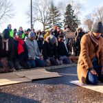 Imam Yusef Abdulle leads the afternoon prayer as dozens of demonstrators gather outside of Minneapolis-St. Paul Airport to protest deportation flights that regularly fly out of MSP Wednesday, Dec. 3, 2025. (Photo by Nicole Neri/Minnesota Reformer)