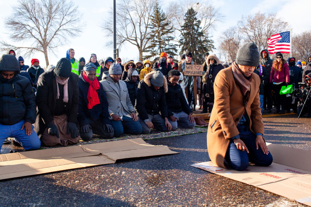 Imam Yusef Abdulle leads the afternoon prayer as dozens of demonstrators gather outside of Minneapolis-St. Paul Airport to protest deportation flights that regularly fly out of MSP Wednesday, Dec. 3, 2025. (Photo by Nicole Neri/Minnesota Reformer)