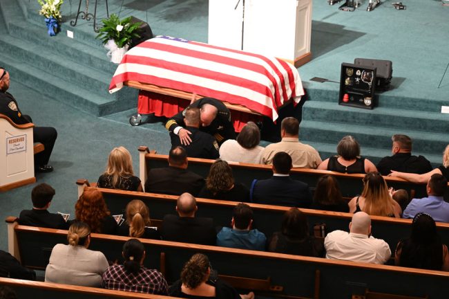 Sheriff Rick Staly embracing Police Chief Tom Foster after Staly's Eulogy: he'd spoken of the bewilderment of having to deliver the second eulogy for a fallen officer in Flagler in three months, from the same spot, a reference to the death of Corrections Deputy Paul Luciano in late August. (© FlaglerLive)