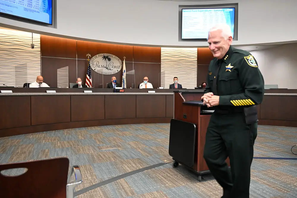 The Flagler County Sheriff's Office's Mark Strobridge had reasons to smile--10 reasons--as he walked away from the podium after answering questions from Palm Coast City Council members this evening. The council, with some disagreement, had granted the 10 additional deputies Sheriff Rick Staly requested. The council had a harder time settling on a property tax rate. (© FlaglerLive)