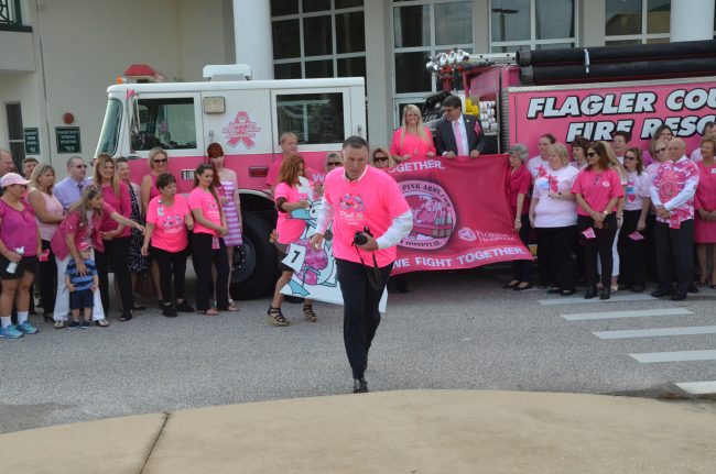 Always on the offensive, John Subers, center, is the commander in chief pof the Pink Army and the executive director of the Florida Hospital Flagler Foundation, which leads the annual fund-raising drive for Breast-Cancer Awareness Month. Subers this morning was getting set to take the picture of all those who'd gathered for the flag-raising in front of the Government Services Building just after 8 a.m.