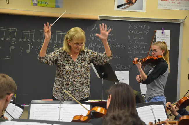 Flagler Youth Orchestra Artistic Director and Conductor Sue Cryan during Wednesday's rehearsal for the FYO's top orchestra's performance on Saturday, with Evan Hernandez, right, the concertmaster, performing a baroque duet. (© FlaglerLive)