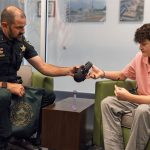 Commander Ryan Emery hands a teenager a pair of earmuffs from the sensory support kit. (FCSO)