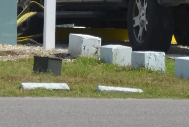 The suspicious ammo box left in the grass at the foot of the Barracuda Bay motel sign in Flagler Beach this afternoon. click on the image for larger view. (c FlaglerLive)