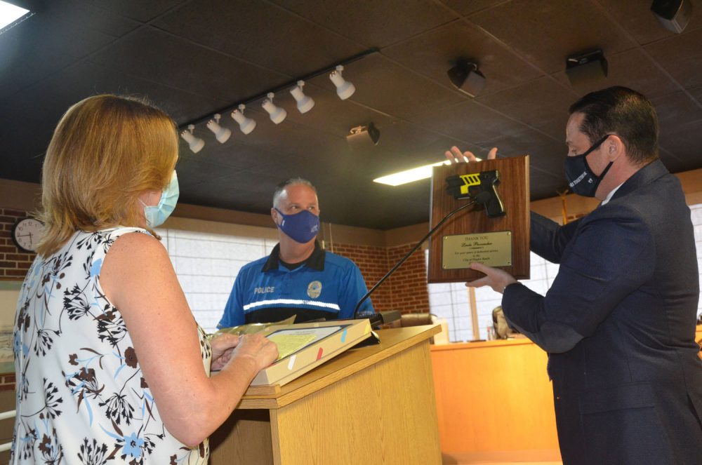 Flagler Beach Commission Chairman Eric Cooley and Police Chief Matt Doughney presenting ex-Mayor Linda Provencher with the taser she's longed for over the years. (© FlaglerLive)