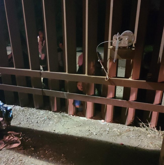 Migrants waiting for access into the country at a gate in the fence a quarter mile in from the border. (Rick Staly)