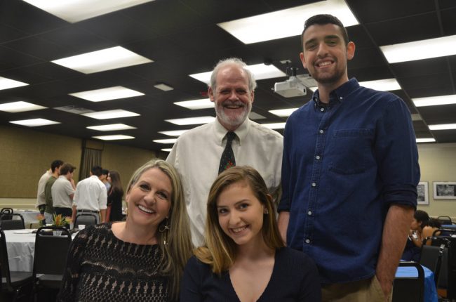 Bobi Mason, left, saw all three of her children through FPC's IB program, and all three are now in college, as is she: her daughter Elizabeth, right, graduated at 17 last May with the school's top weighted GPA and is now attending Wellesley College. Her twins Forrest--standing at right, next to FPC Math teacher Warren Sanson--and Alexandria graduated in 2014. Forrest is at UF, which Bobbi is also attending, and Alexandria is at Stetson. Click on the image for larger view. (© FlaglerLive)