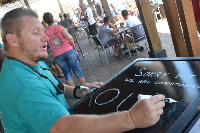 Tortugas owner Scott Fox had been giving away free eclipse glasses, but they went fast and he had to write out a sign that he'd run out: the party drew teeming patrons, however. Click on the image for larger view. (© FlaglerLive)