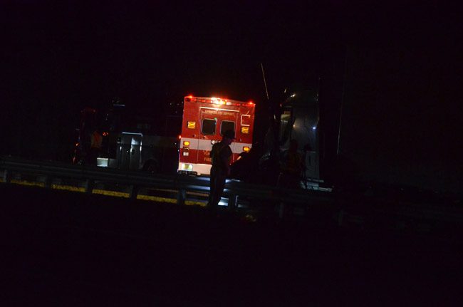 A familier sight at traffic crashes and fatalities involving pedestrians in Palm Coast: a dark street, a cop, an ambulance. (© FlaglerLive)