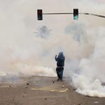 Smoke and tear gas surround a protester in Los Angeles on June 7, 2025, amid confrontations between immigration rights advocates and law enforcement personnel.