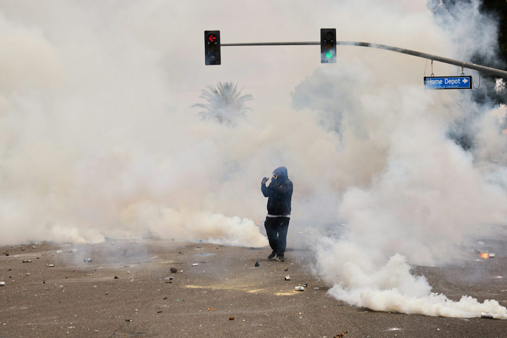 Smoke and tear gas surround a protester in Los Angeles on June 7, 2025, amid confrontations between immigration rights advocates and law enforcement personnel.