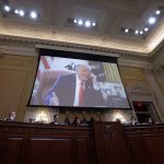 In this photograph, former President Donald Trump appears on a video screen above members of the Select Committee to Investigate the January 6th Attack on the U.S. Capitol.